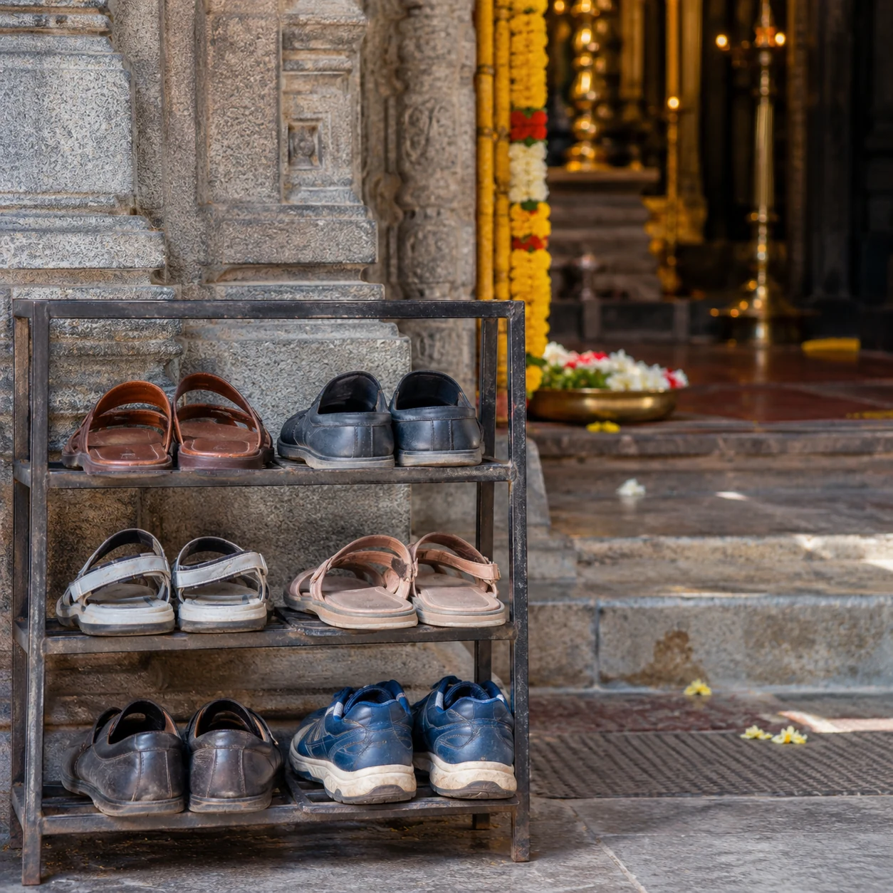 Illustration of pairs of shoes arranged on a rack beside a temple entrance.